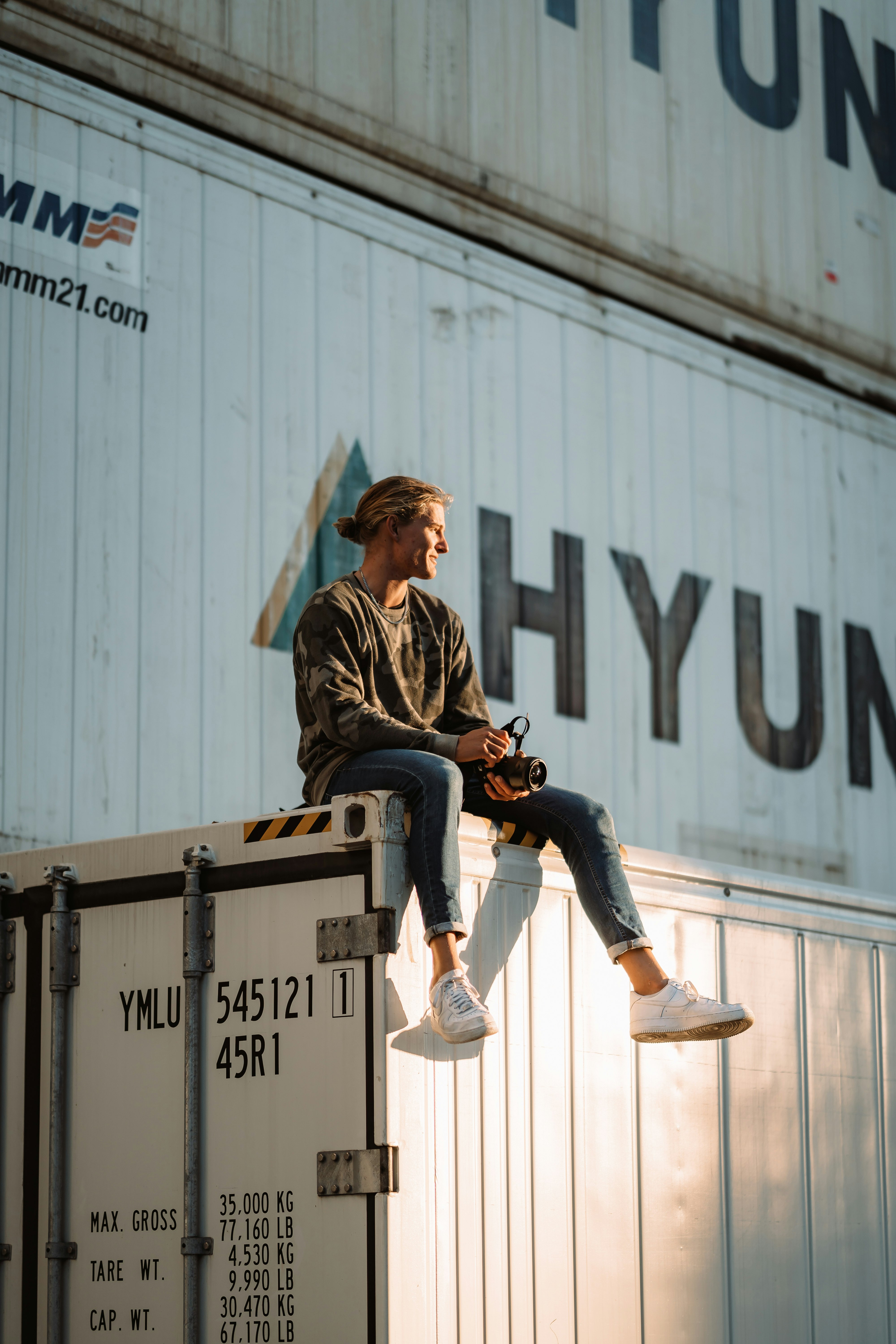 man in brown and black plaid dress shirt and blue denim jeans sitting on white box